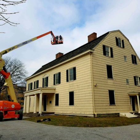 A crane lifting workers to a roof of a house