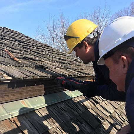 Workers in hard hats working on restoring an old wooden roof
