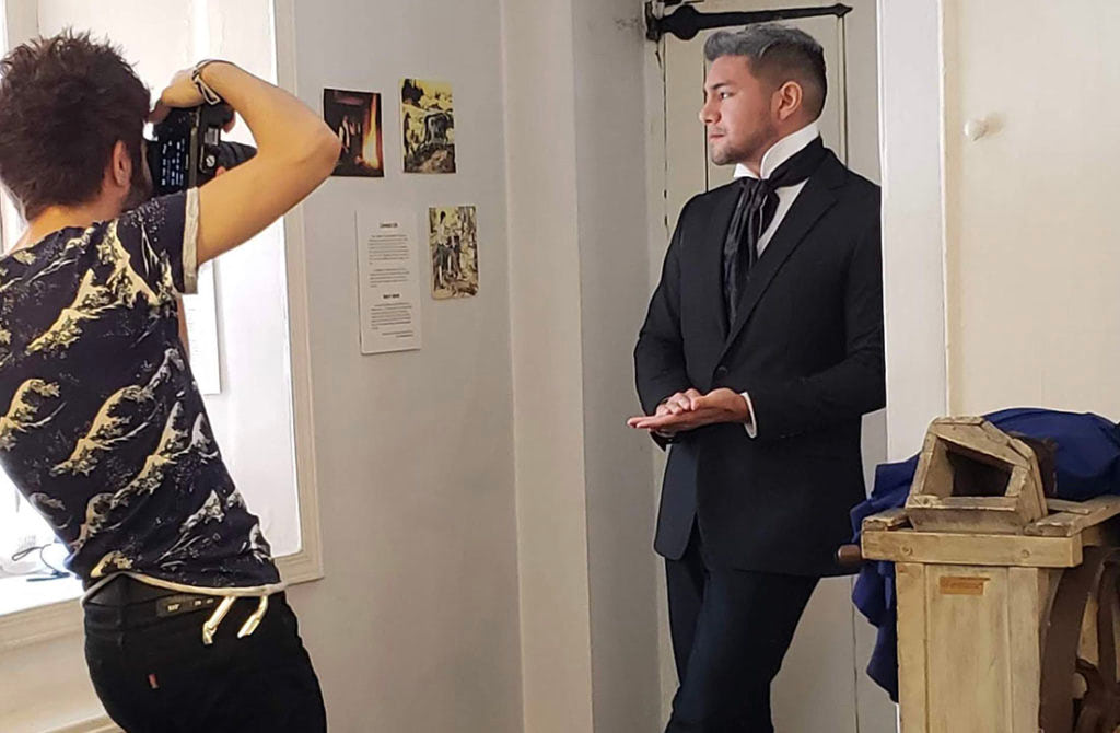 A man in a black suit being photographed by a photographer