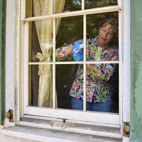 Woman cleaning an old window in blue rubber gloves