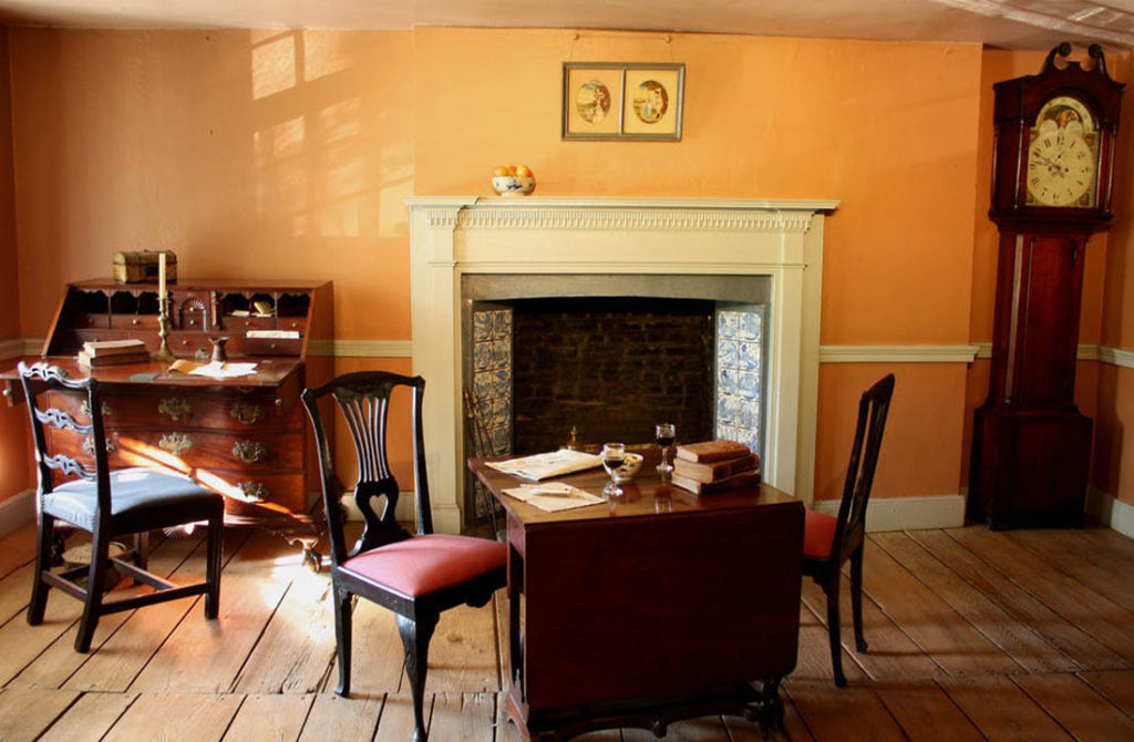 Fireplace inside an orange room of the Dyckman Farmhouse Museum