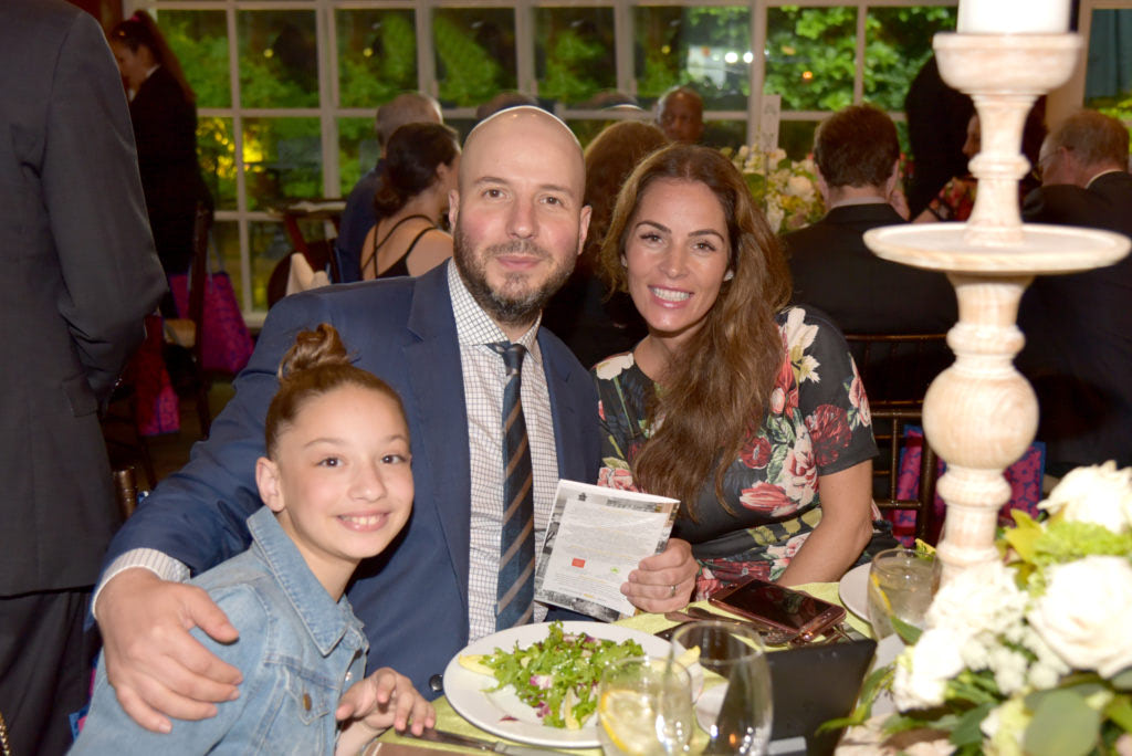 A couple with a daughter posing for a photograph at a dinner table
