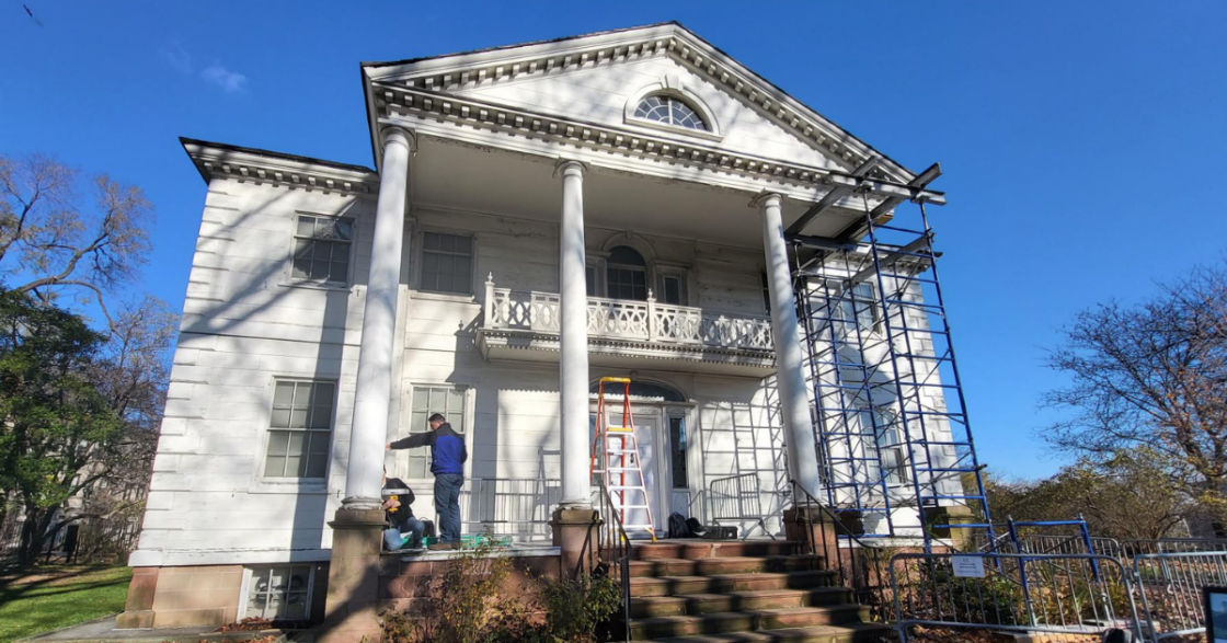 White historic mansion with pediment and columns.